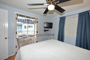 Relax in this inviting room with a large bed, ceiling fan, and flat-screen TV, plus a balcony with a table outside.