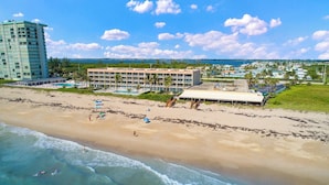 A beachfront hotel with a pool, beach umbrellas, and a view of the ocean.