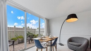 A modern living room with a dining area, large windows, and a grey armchair.