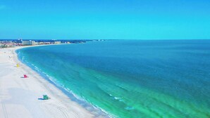 A beach with clear turquoise water, a sandy shore, and a few beach umbrellas.
