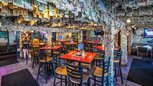 Un restaurante con mesas cubiertas de billetes de dólar, una pantalla de televisión y una pizarra de menú.