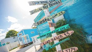 Un cartel con indicaciones a varios lugares, incluyendo Siesta Key Beach, Nueva York, Lido Beach y Alaska.