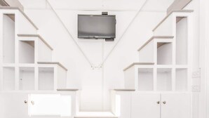 Una habitación blanca con estantes empotrados, un televisor de pantalla plana y una mesita pequeña.