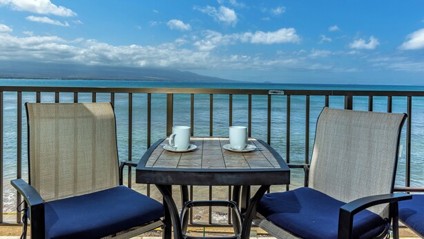 Uma mesa com duas chávenas brancas e vista para o mar.