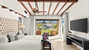 A bedroom with a large bed, a TV, and a balcony with a pool view.