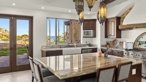 A modern kitchen with a large island, wooden cabinets, and a view of the outdoors.