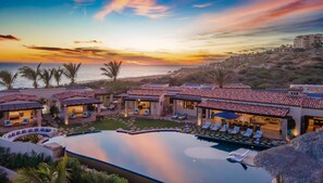 Relax in a serene pool area surrounded by lush gardens and palm trees, with outdoor spaces and comfortable seating.