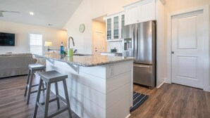 A modern kitchen with a central island, stainless steel appliances, and white cabinetry. - 🌊SeaWave: Spacious Pet-Friendly House with Deck & Grill | Walk 2 Beach🌊 (Kure Beach)