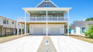 A two-story house with a balcony, a garage, and a driveway. - 🌊SeaWave: Spacious Pet-Friendly House with Deck & Grill | Walk 2 Beach🌊 (Kure Beach)