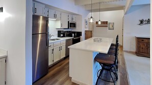 Une cuisine moderne avec des meubles blancs, des appareils en acier inoxydable et un îlot central doté de tabourets de bar.