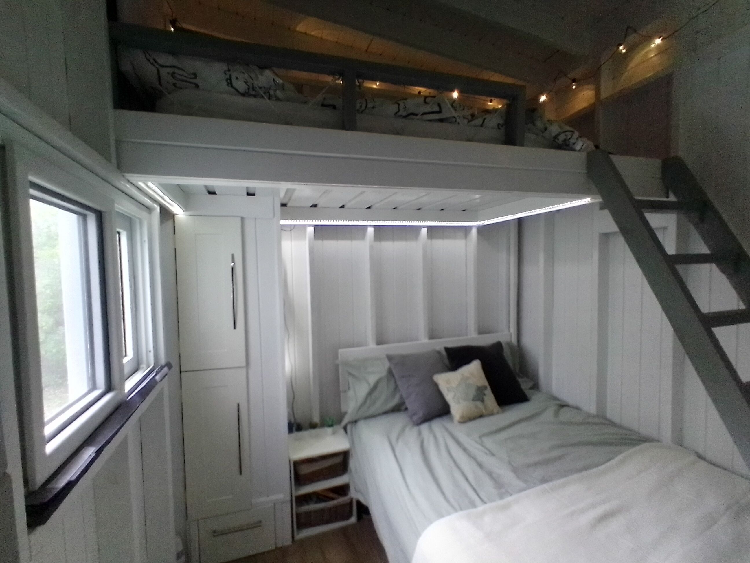 A compact bedroom with a bunk bed, built-in wardrobe, and a window.