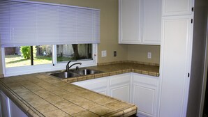 A kitchen with white cabinets, a double sink, and a window with blinds. - Large house in Silicon Valley - 40 min from San Francisco near Levi's Stadium (Santa Clara)