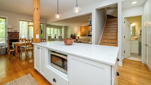 A modern kitchen with a central island, wooden accents, and a view of the living area. - Newly Updated Union Pier Home with Deeded Beach Access! (Union Pier)
