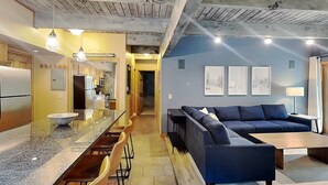 A modern kitchen with a central island, a dining area with chairs, a sofa, and a coffee table. - 🌲Timberline C2E Deluxe 2-Bedroom ~Hot Tub~Pool~WiFi~Ski-in/out~Local Shuttle🌲 (Snowmass Village)