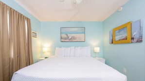 Ein Hotelzimmer mit einem Bett, zwei Wandleuchten, einem Deckenventilator und zwei gerahmten Bildern an der Wand.