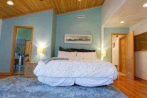 Une chambre avec un grand lit, un plafond en bois et un tableau accroché au mur.