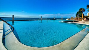 Ein Swimmingpool mit klarem, blauem Wasser, umgeben von einer Betonplattform und einem Metallgeländer.