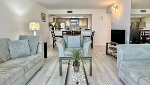 A modern living room with a sofa, a coffee table with a plant, and a TV.