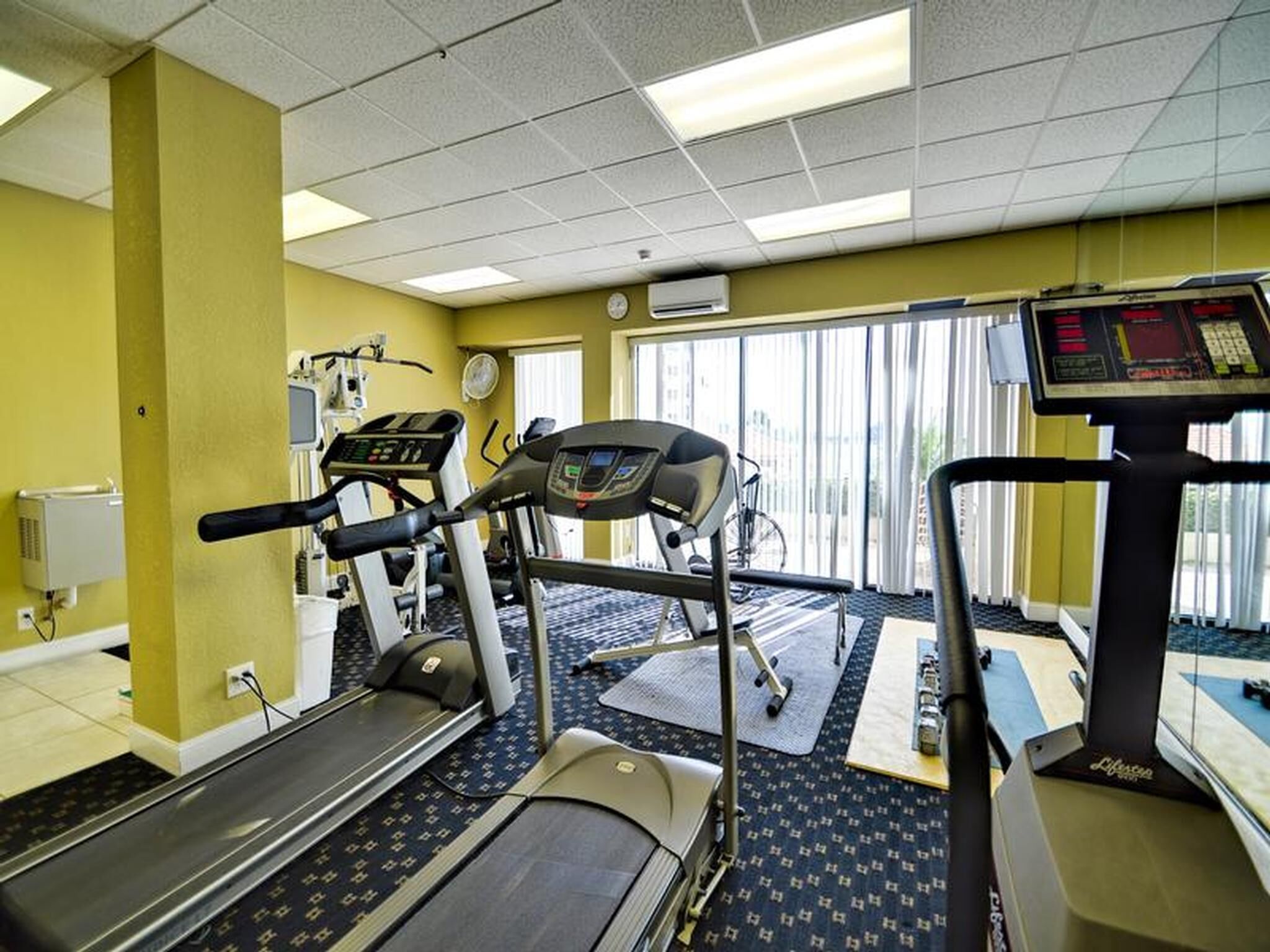 Et fitnesscenter med løbebånd, motionscykel og romaskine.
