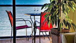 A balcony with a table and chairs overlooking the ocean.