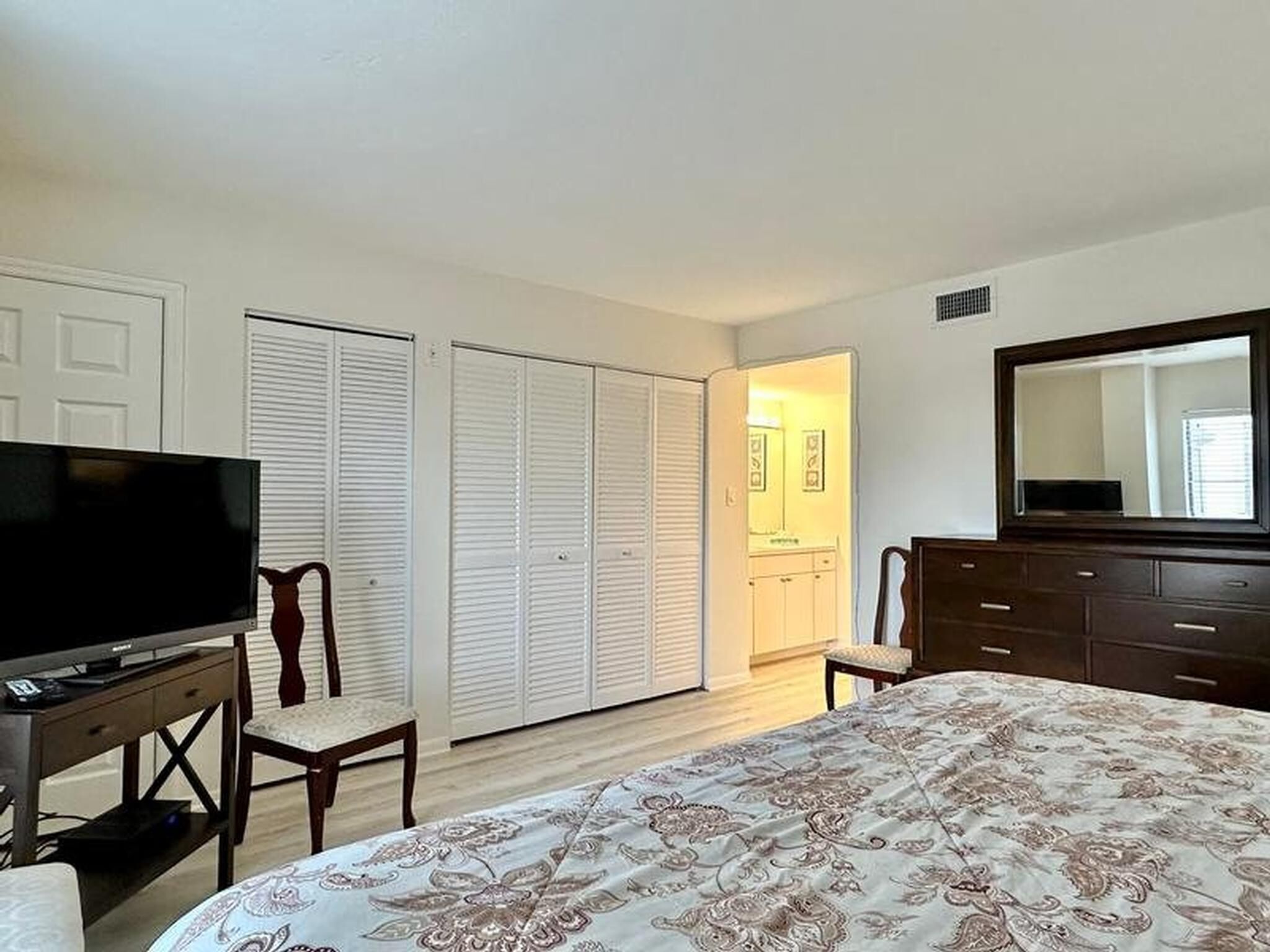 A bedroom with a bed, a TV, a dresser, and a closet.