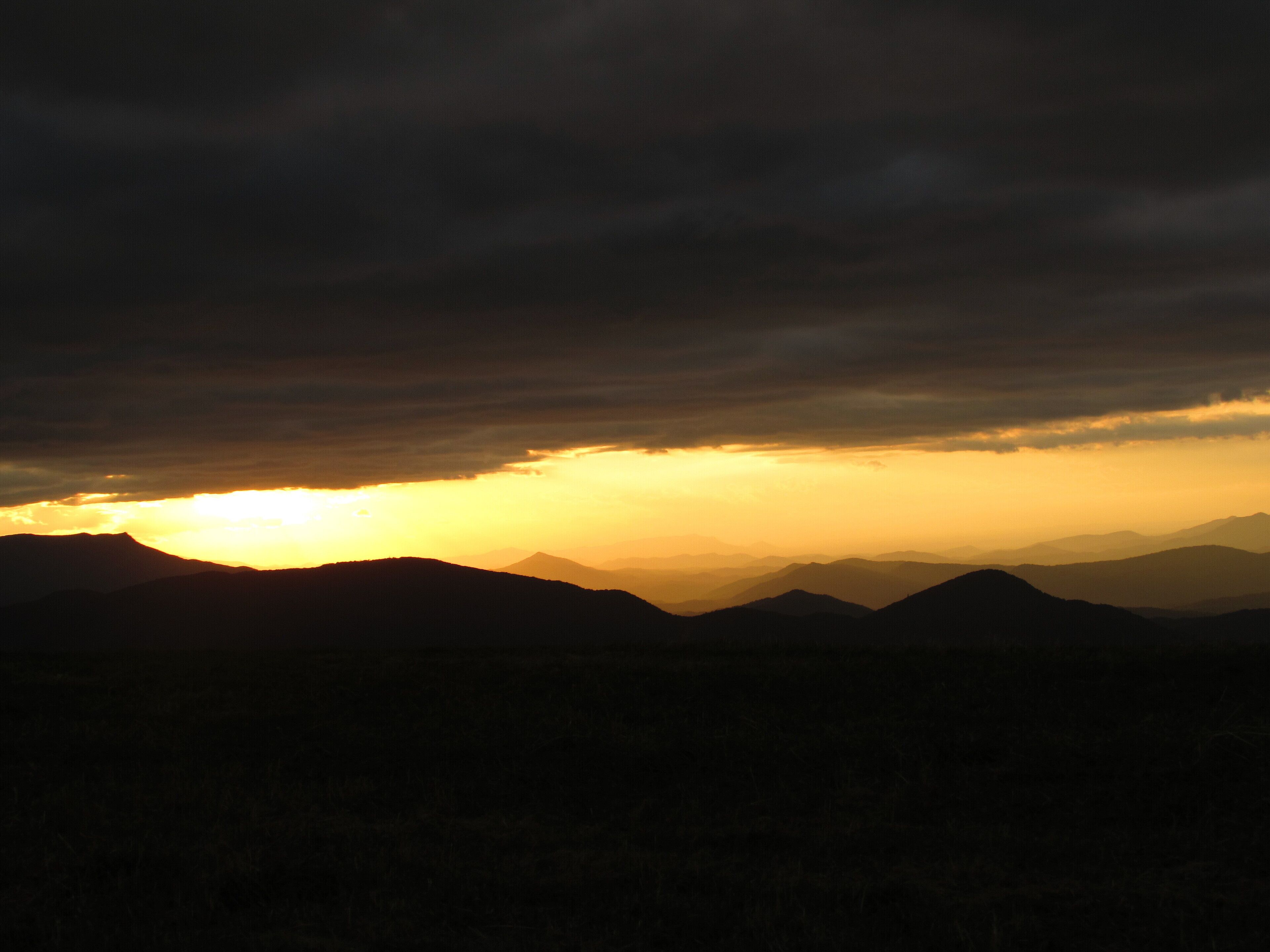 Un paysage montagneux au coucher du soleil, avec un ciel dégagé.