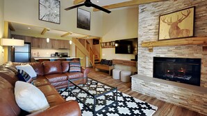 Ein geräumiges Wohnzimmer mit Ledersofa, Kamin und einer Küche im Hintergrund.