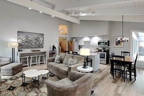 A modern living room with a sofa, coffee table, and a dining area with chairs and a table. - 🌲Timberline D3E Deluxe 3-Bedroom plus Loft ~Hot Tub~Pool~WiFi~Ski-in/out~Local Shuttle🌲 (Snowmass Village)