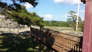 A wooden deck with a railing overlooking a rocky area with trees. - Calico Rock Cabin-500 Calico St 390 Chessmond Ferry Rd viewing the White River  (Calico Rock)