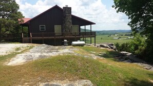 A rustic cabin with a stone chimney, a wooden deck, and a view of rolling hills. - Calico Rock Cabin-500 Calico St 390 Chessmond Ferry Rd viewing the White River  (Calico Rock)