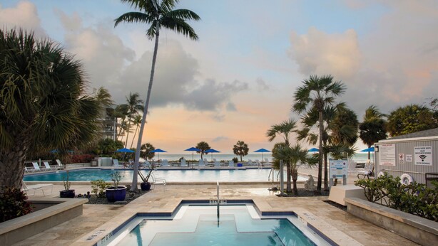 A pool area with lounge chairs, palm trees, and a view of the beach. - 2 Bdrm Monthly ocean view, expansive porch ,renovated unit Key West Fabulous (Key West)
