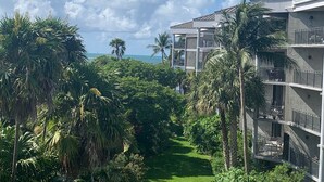 A multi-story hotel with balconies, surrounded by lush greenery and a view of the ocean. - 2 Bdrm Monthly ocean view, expansive porch ,renovated unit Key West Fabulous (Key West)
