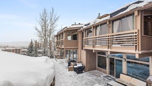 A modern building with multiple balconies, large windows, and a covered outdoor seating area.