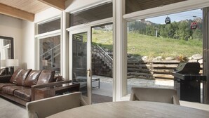 A modern living room with a leather sofa, a dining table, and a grill outside.