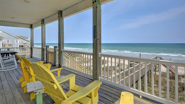 A covered deck with yellow chairs and a view of the beach. - Five Bedroom Oceanfront Home - Just Chilln (North Topsail Beach)