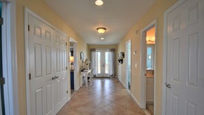 A hallway with white doors, a tiled floor, and a ceiling light. - Five Bedroom Oceanfront Home - Just Chilln (North Topsail Beach)