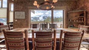 A dining area with a large table, wooden chairs, and a chandelier.