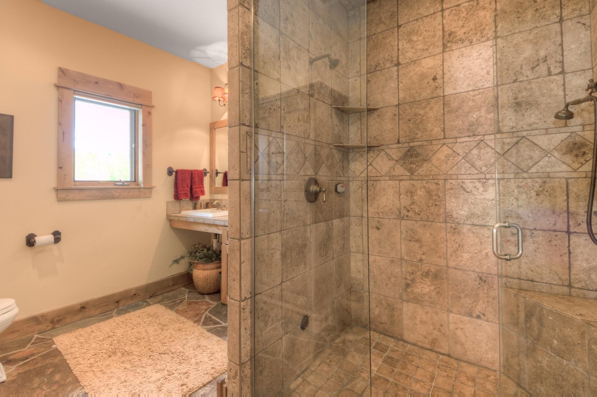 Een badkamer met een douche, een wastafel en een raam.