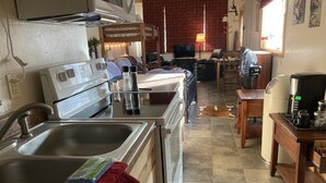Una cocina con lavaplatos, estufa y zona de comedor.