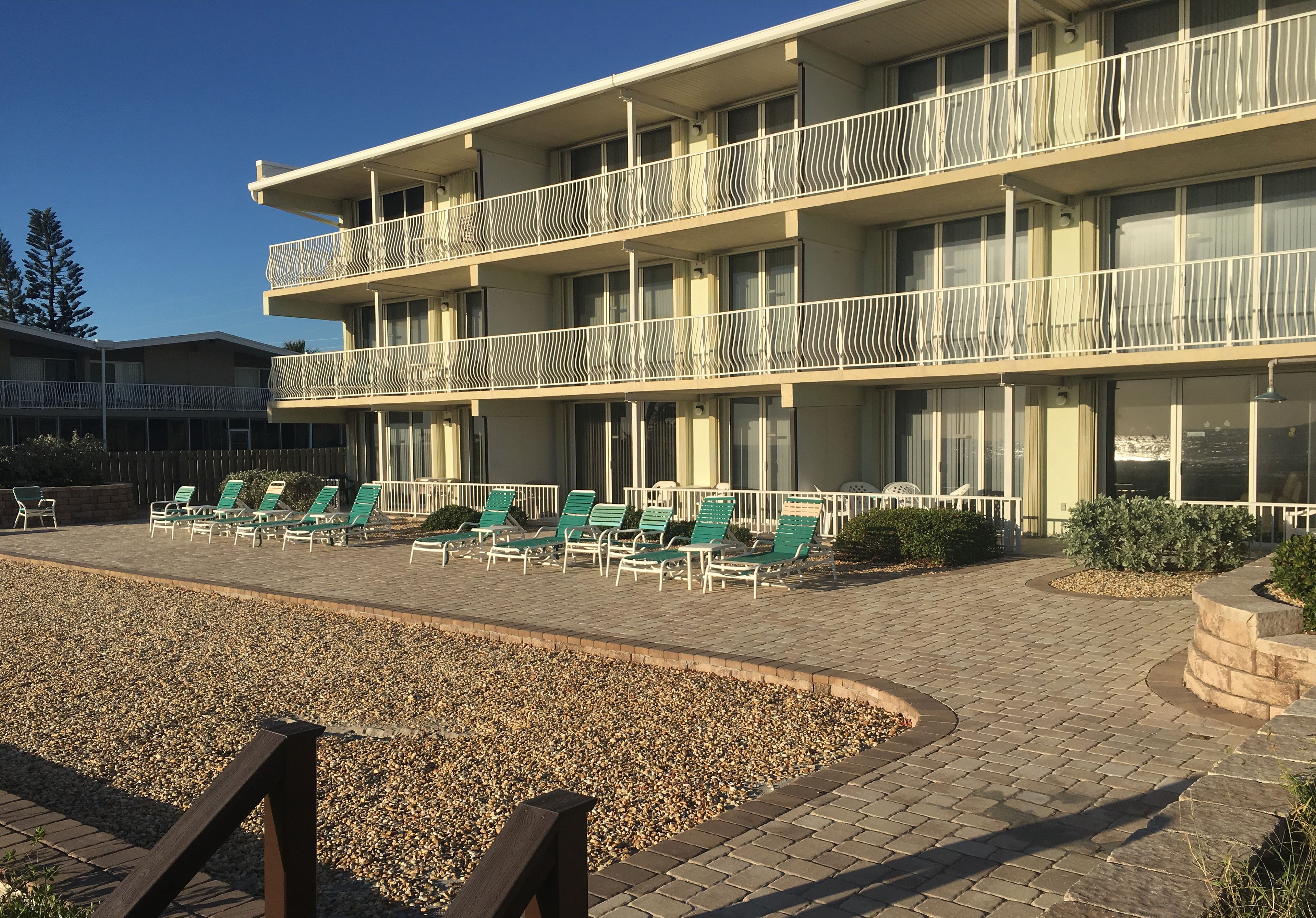 Un hotel de varios pisos con asientos al aire libre y vista al océano.