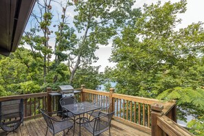 A wooden deck with a grill and chairs overlooking a lake. - Tree Top 16 - Two Bedroom House, Sleeps 6 (Four Seasons)