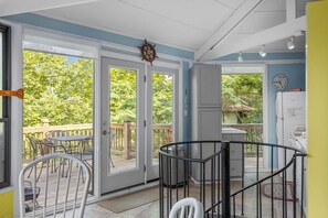 A room with a view of a wooden deck and greenery, a clock, a 'NO SMOKING' sign, and a refrigerator.