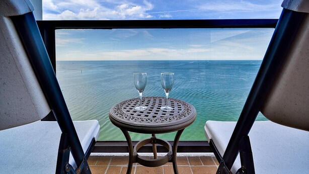 Un balcon avec une table et deux chaises, donnant sur la mer.