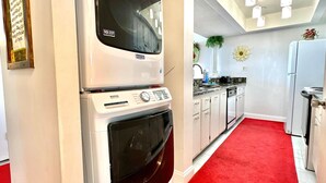 Une cuisine de taille modeste, avec un tapis rouge, un four Maytag, un four à micro-ondes et un réfrigérateur.