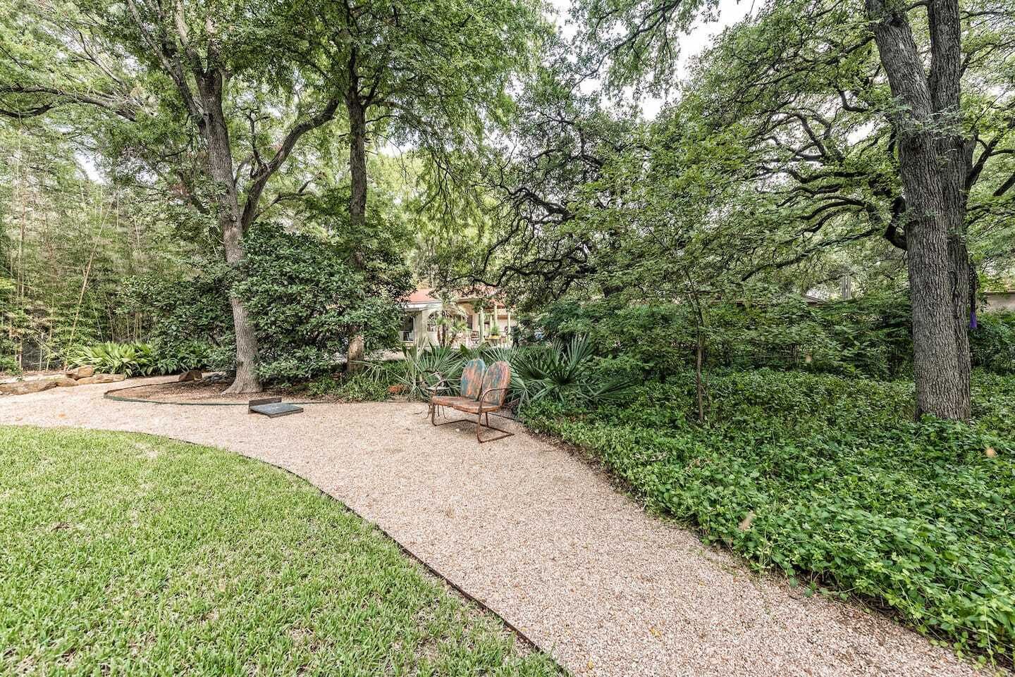 Ein Garten mit Kiesweg, einer Bank und einem Gazebo.