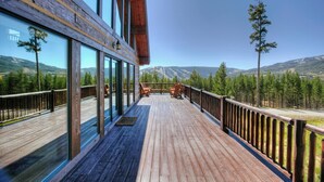 Eine Holzterrasse mit Blick auf Berge und Bäume.