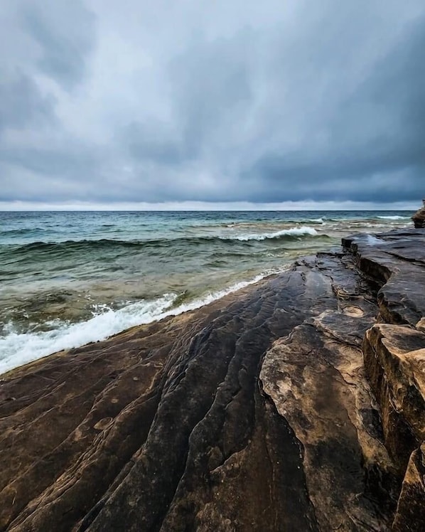 Experience the serene coastal landscape with crashing waves against the rocky shoreline.