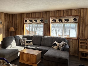Relax in this inviting living room with a large sofa, coffee table, and views of the surrounding landscape.