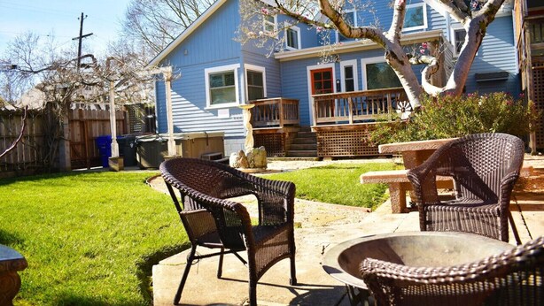 A backyard with a patio area, wicker furniture, and a house with blue siding and a red door. - Beautiful Magnolia House in Napa Valley! (Napa)