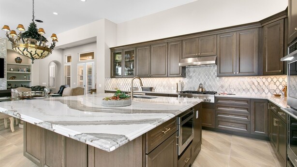 A spacious kitchen with a large marble island, dark wooden cabinets, and modern appliances. - 3 Bedroom, PGA West home, Private Pool & Spa, #063306 (La Quinta)